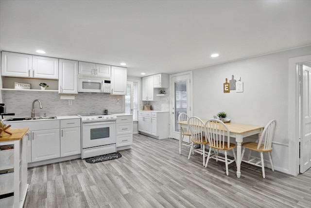 kitchen featuring white cabinets, light hardwood / wood-style flooring, backsplash, and white appliances