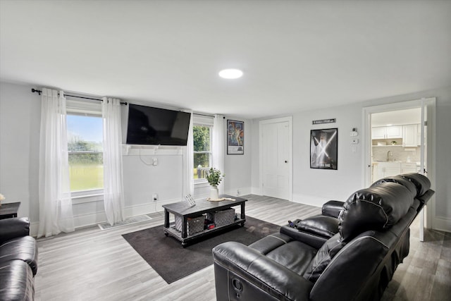 living room with sink, light hardwood / wood-style flooring, and a healthy amount of sunlight