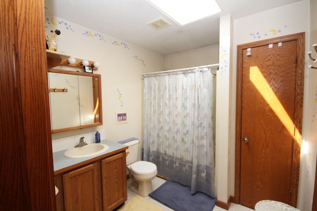 bathroom featuring vanity, walk in shower, toilet, and a skylight