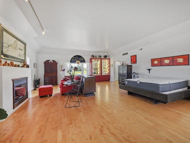 living room with vaulted ceiling, track lighting, and light hardwood / wood-style flooring