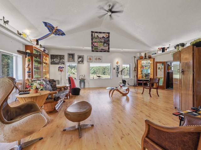 living room featuring ceiling fan, light hardwood / wood-style flooring, and lofted ceiling