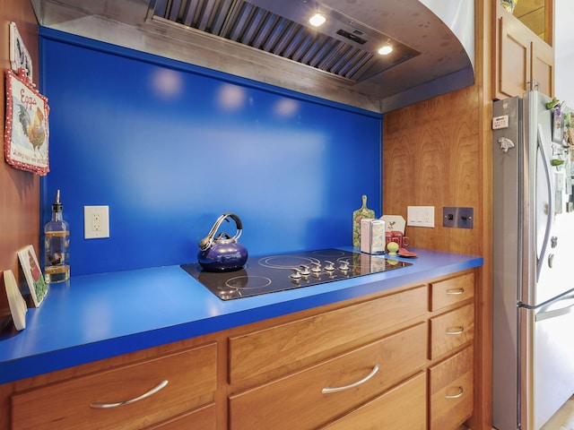 bar featuring custom range hood, stainless steel fridge, and black electric cooktop