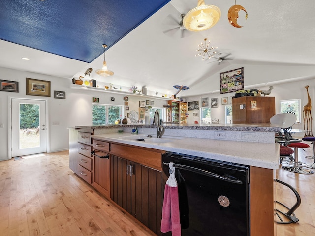 kitchen featuring a wealth of natural light, light hardwood / wood-style flooring, lofted ceiling, and dishwasher