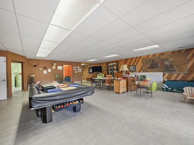 recreation room with a drop ceiling, wooden walls, concrete floors, and billiards