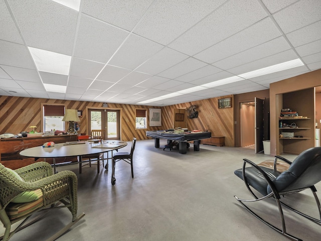 interior space with wooden walls, concrete floors, and a paneled ceiling