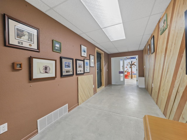 hallway with a drop ceiling and concrete floors