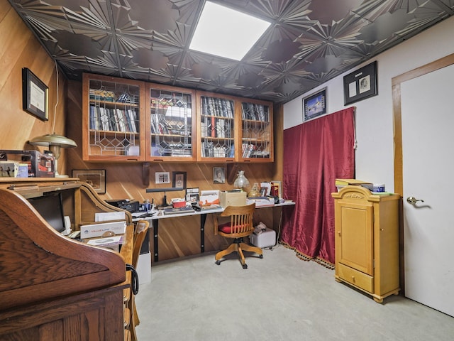 carpeted office space with wooden walls and built in desk