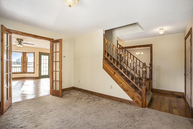 interior space featuring ceiling fan with notable chandelier, french doors, a textured ceiling, and hardwood / wood-style flooring