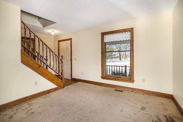 carpeted entrance foyer featuring a textured ceiling