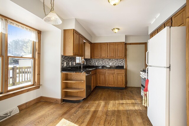 kitchen featuring sink, stainless steel dishwasher, white refrigerator, backsplash, and hardwood / wood-style floors