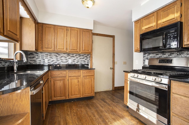 kitchen featuring decorative backsplash, appliances with stainless steel finishes, dark stone counters, sink, and dark hardwood / wood-style floors