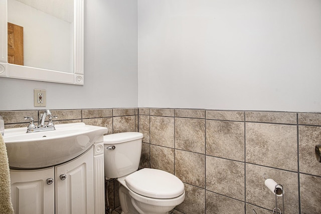 bathroom featuring vanity, tile walls, and toilet