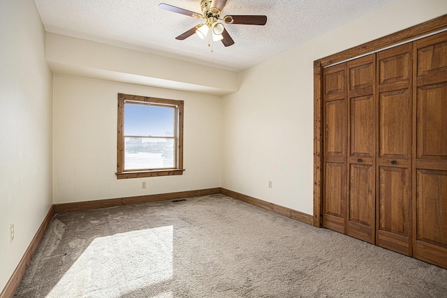 unfurnished bedroom with a textured ceiling, carpet floors, and ceiling fan