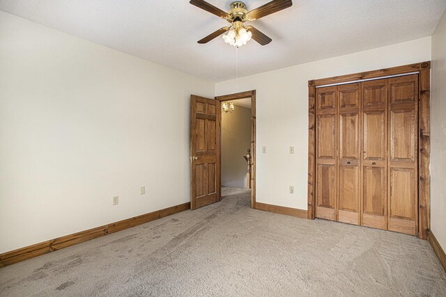 unfurnished bedroom featuring light carpet, a textured ceiling, a closet, and ceiling fan