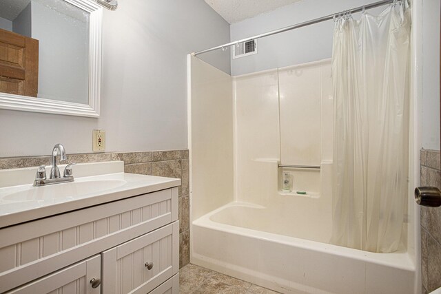 bathroom with vanity, shower / bath combination with curtain, and a textured ceiling