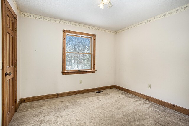 carpeted empty room with a textured ceiling