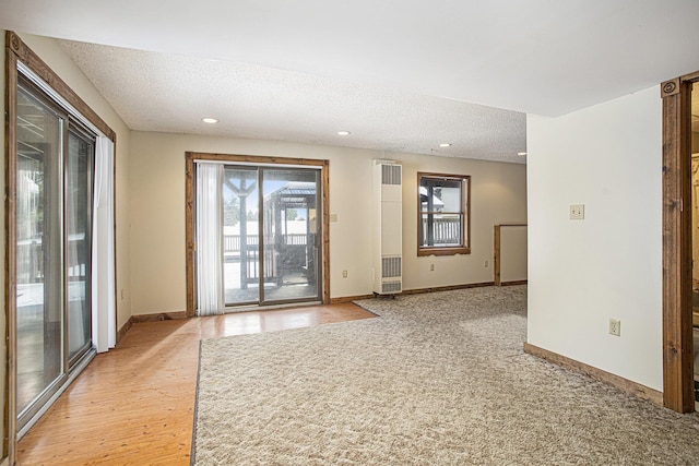 unfurnished room featuring light wood-type flooring and a textured ceiling