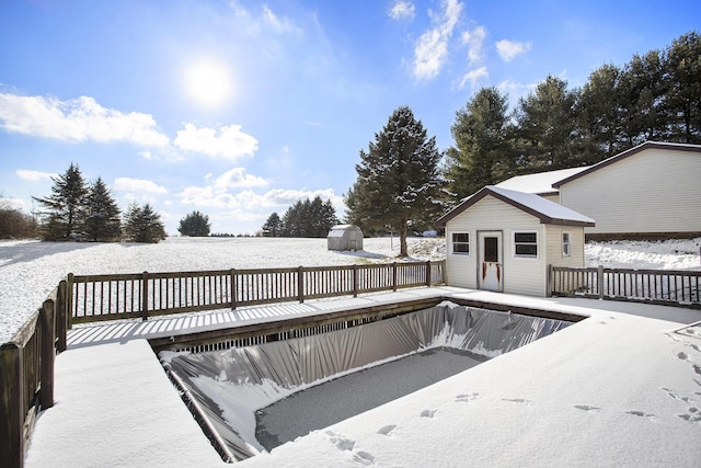 snow covered pool with a shed and a wooden deck