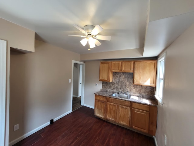 kitchen featuring ceiling fan, backsplash, sink, and dark wood-type flooring