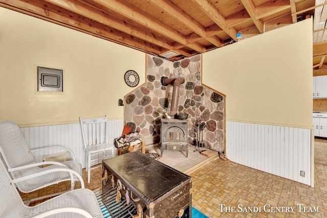 sitting room featuring beamed ceiling, wooden ceiling, a wood stove, and tile patterned flooring