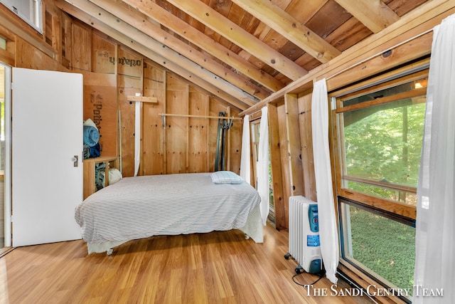 bedroom with wooden walls, light hardwood / wood-style flooring, wood ceiling, and radiator