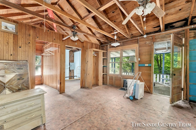 misc room with wood walls, ceiling fan, and vaulted ceiling