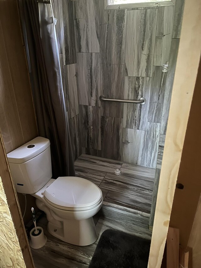 bathroom featuring tiled shower and toilet