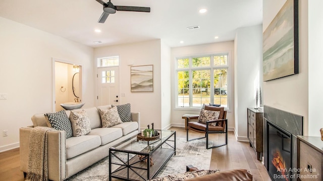 living room with ceiling fan, a healthy amount of sunlight, and light wood-type flooring