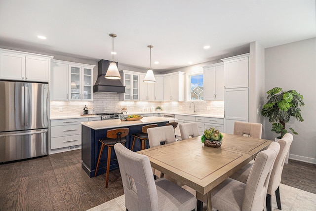 kitchen with dark wood-type flooring, freestanding refrigerator, light countertops, and custom exhaust hood