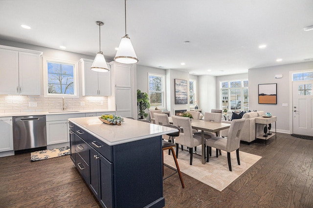 kitchen with light countertops, dark wood-type flooring, white cabinetry, a sink, and dishwasher