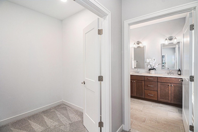 full bath with double vanity, baseboards, and a sink