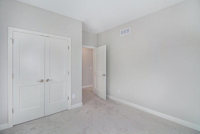 unfurnished bedroom with carpet floors, a closet, visible vents, and baseboards