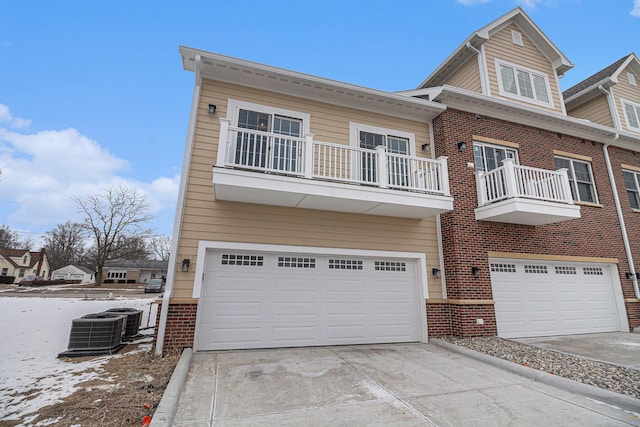 view of front of home featuring driveway, brick siding, an attached garage, and central air condition unit