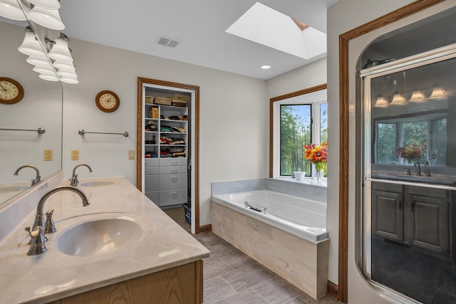 bathroom with plenty of natural light, a bathtub, a skylight, and vanity