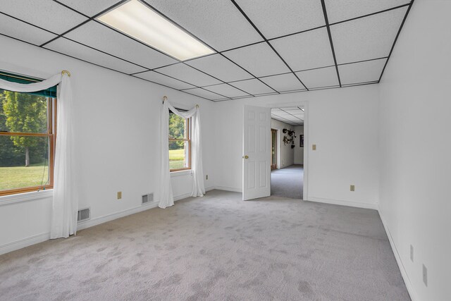 empty room featuring a paneled ceiling and carpet