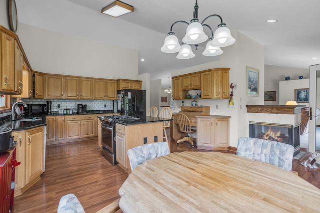 kitchen featuring a multi sided fireplace, dark wood-type flooring, decorative backsplash, and black appliances