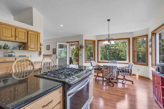 kitchen with dark stone counters, light hardwood / wood-style flooring, plenty of natural light, and stainless steel range with gas stovetop