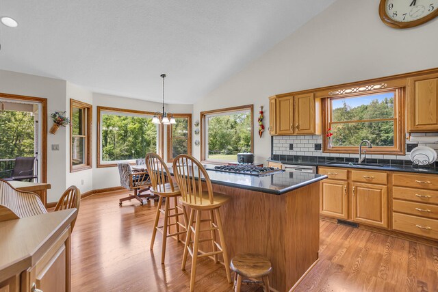 kitchen featuring backsplash, a center island, light wood-type flooring, a chandelier, and pendant lighting