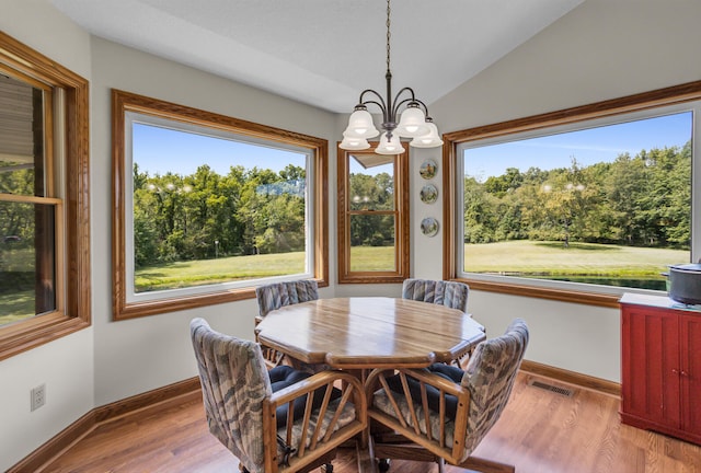 dining room with light wood-type flooring, a notable chandelier, and lofted ceiling