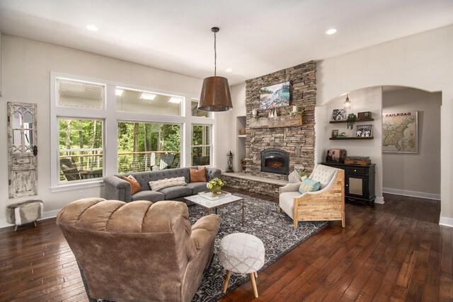 living room with dark hardwood / wood-style flooring and a stone fireplace