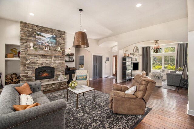 living room featuring a fireplace, built in features, a chandelier, and wood-type flooring