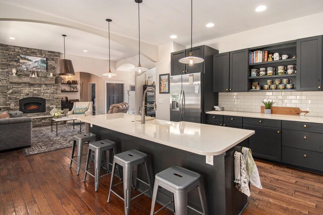 kitchen with tasteful backsplash, a kitchen breakfast bar, dark hardwood / wood-style floors, and a stone fireplace