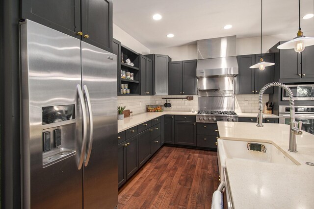 kitchen with dark hardwood / wood-style flooring, appliances with stainless steel finishes, tasteful backsplash, pendant lighting, and wall chimney range hood