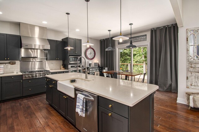 kitchen featuring a kitchen island with sink, dark hardwood / wood-style floors, stainless steel appliances, and tasteful backsplash