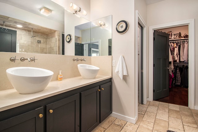 bathroom featuring tile patterned flooring, dual vanity, and tiled shower