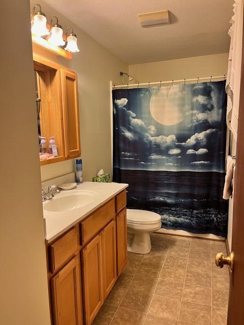 bathroom featuring tile patterned floors, toilet, walk in shower, and vanity