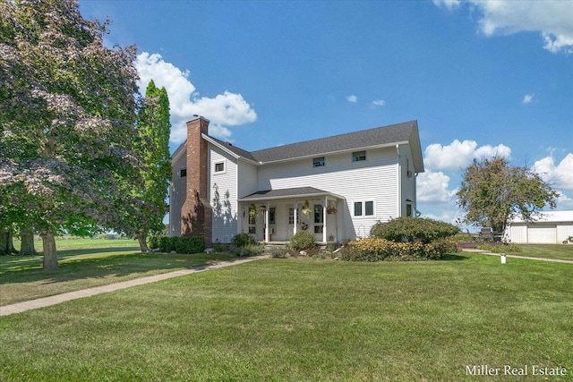 view of front of home featuring a porch, a chimney, and a front lawn