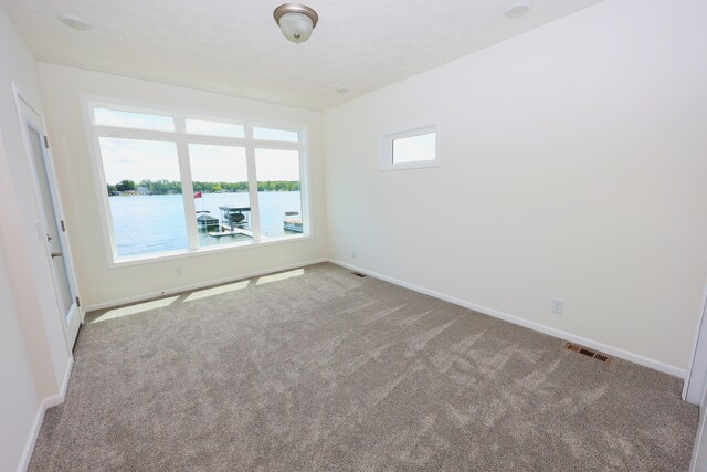 unfurnished room with a water view and light carpet