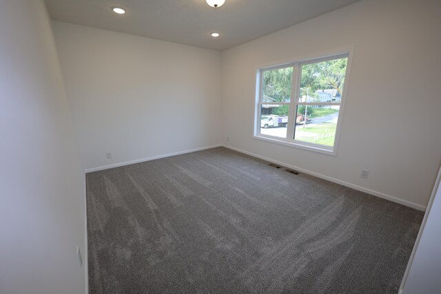 unfurnished room featuring dark colored carpet