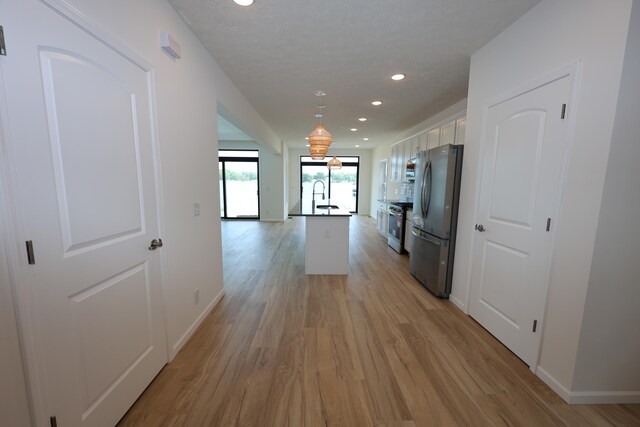 corridor with sink and light hardwood / wood-style flooring